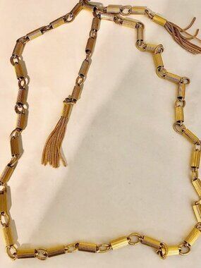 A vintage, unbranded, golden necklace 38 inches long ending in tassels,